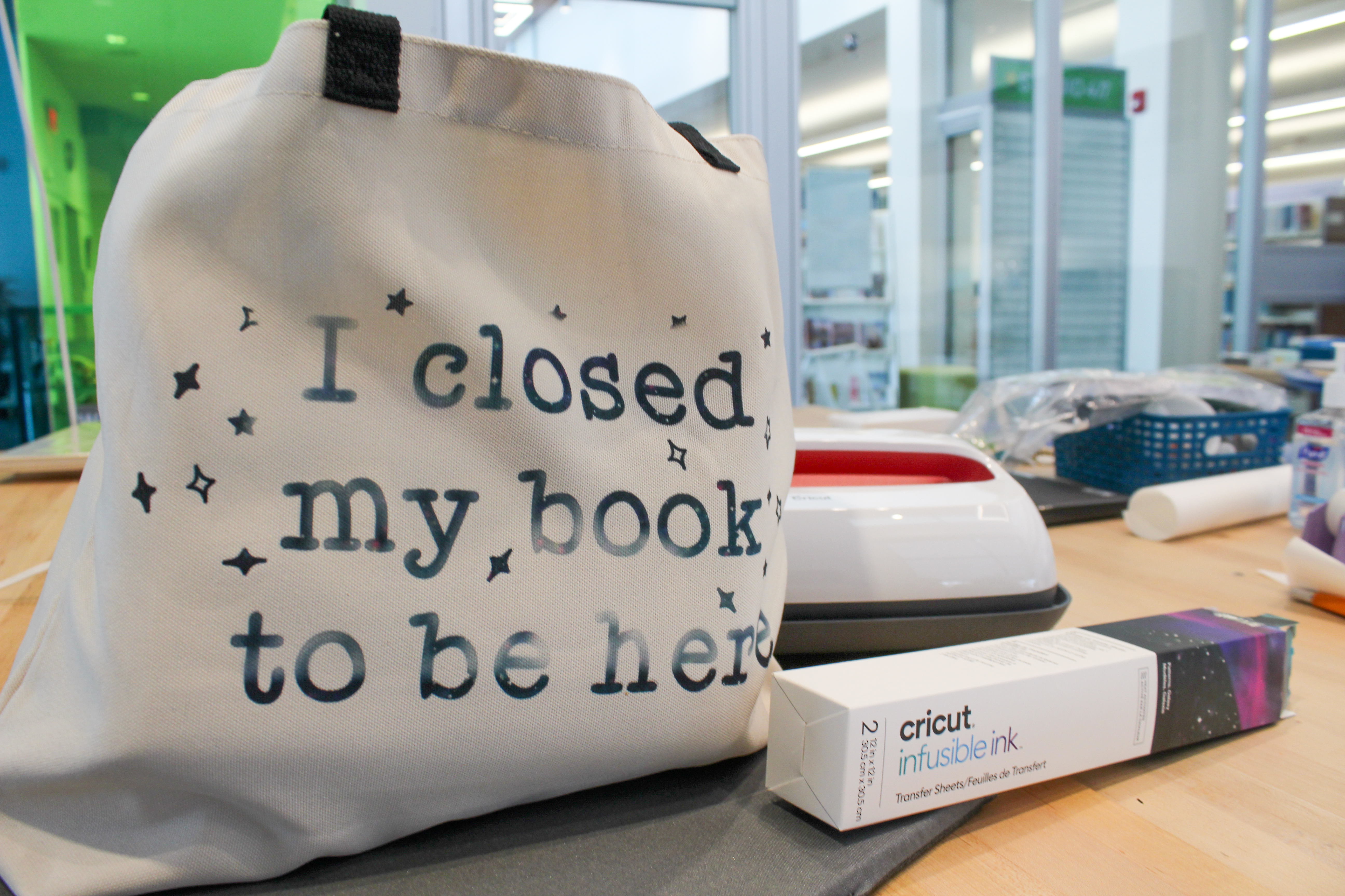 Tote bag with design printed using infusible ink that says I closed my book to be here.